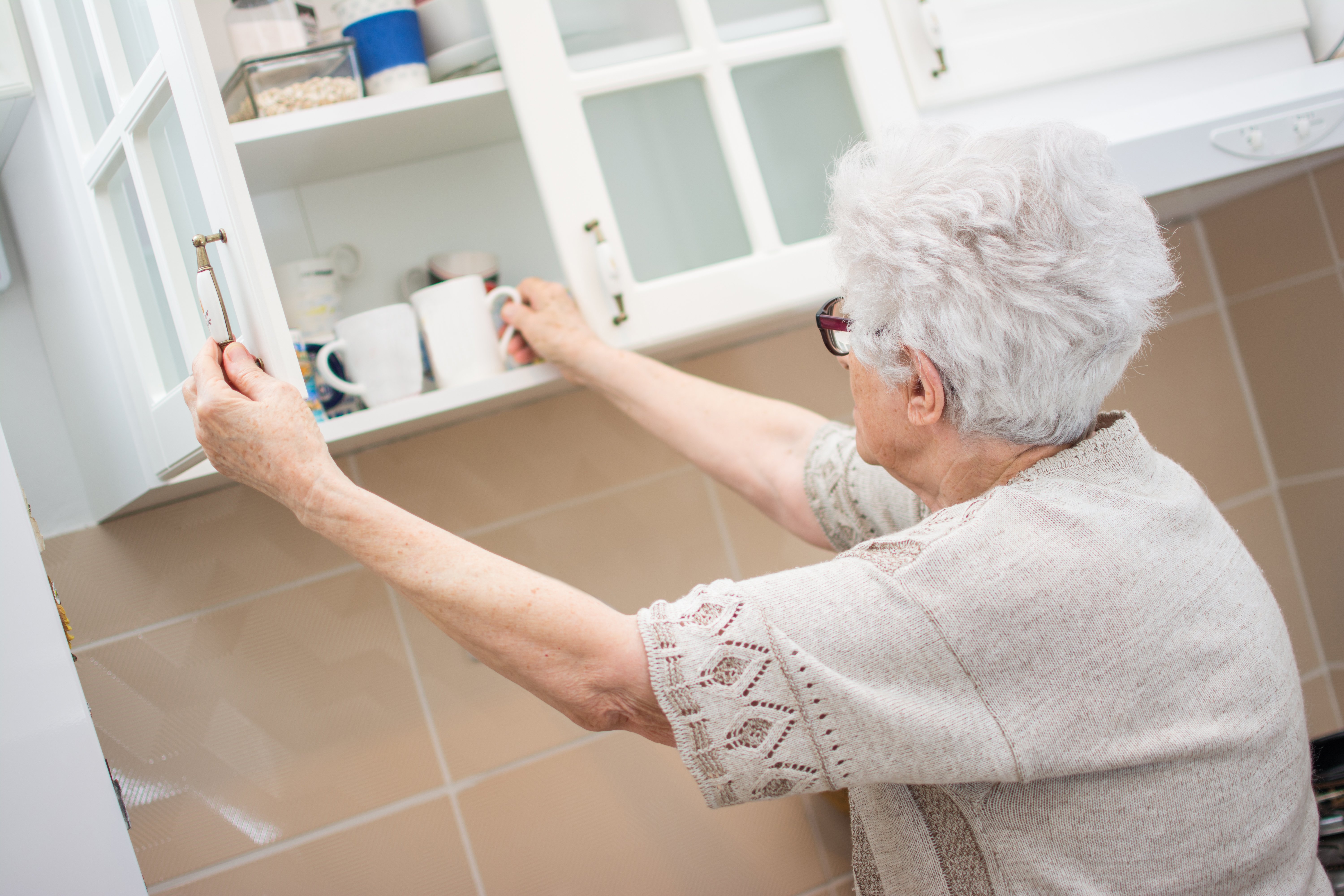 women putting her dishes away in her cabinets