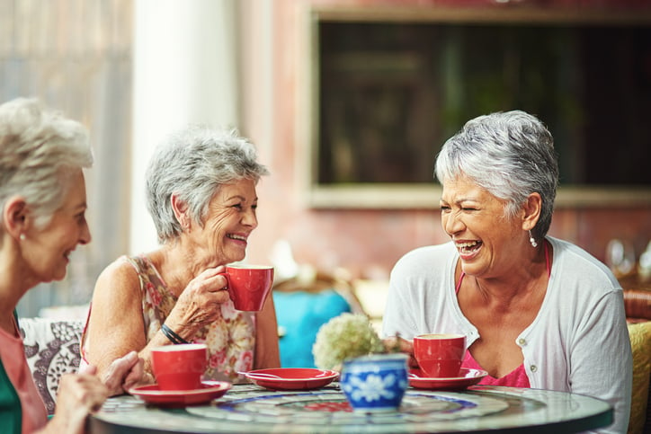 Three women enjoying some coffee while laughing together