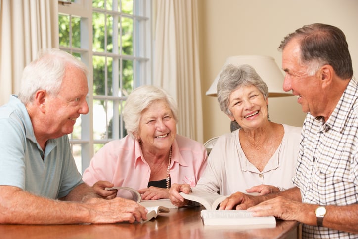 a group of four reading books together and laughing