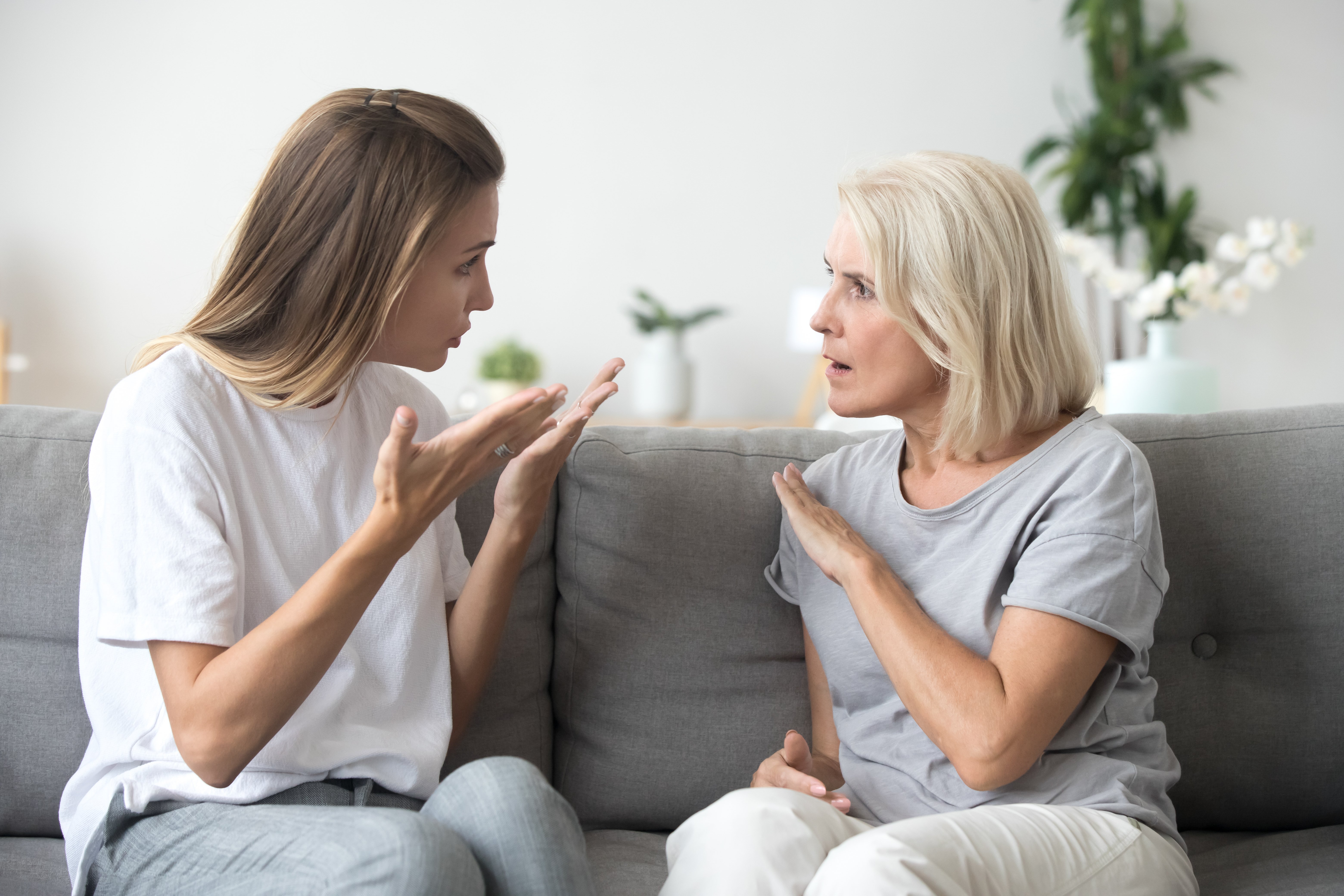 Mother and daughter sitting on a couch having an disagreement with one another