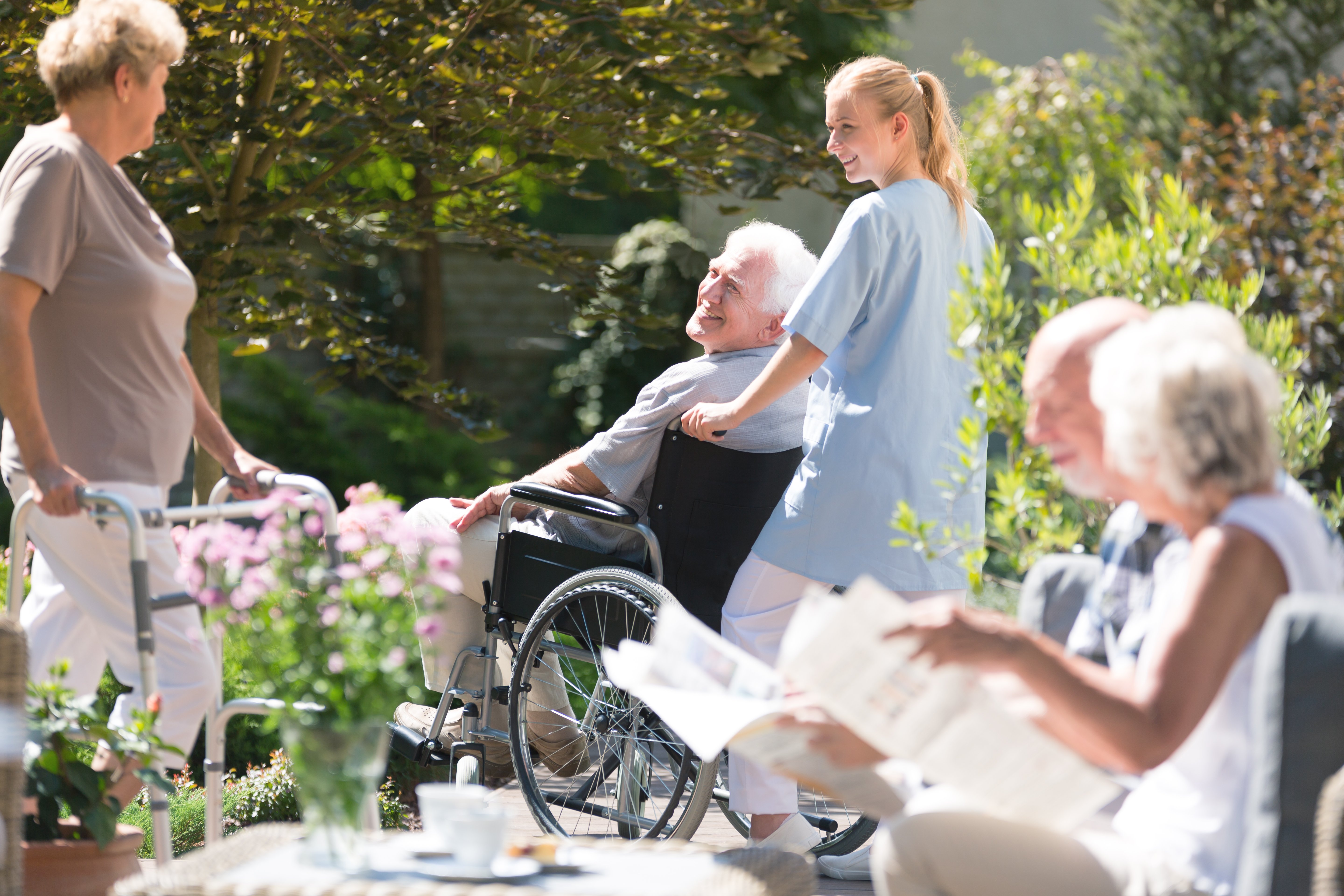 an elderly man getting pushed in his wheelchair outside