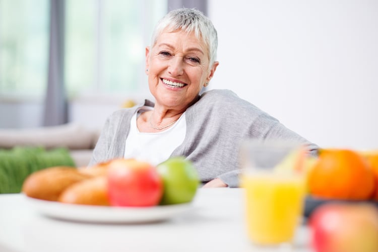 Senior woman in a good mood sitting behind nutritious food