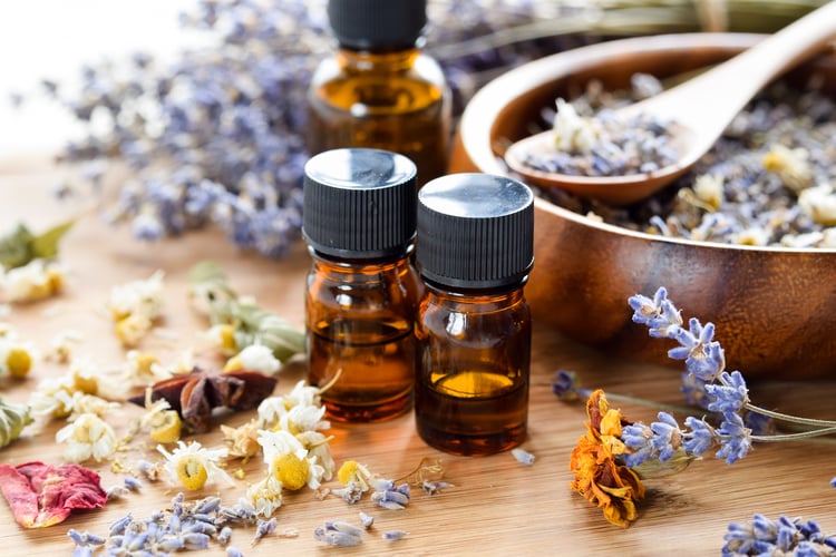 Two bottles of essential oils and various flowers - Holistic Healthcare like aromatherapy is a first approach for seniors living in memory care in highgate temecula california