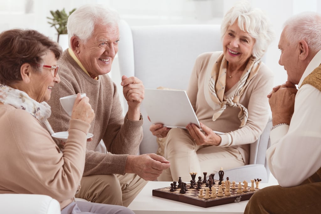 Group of seniors drinking coffee who are playing chess in an Assisted Living Facility