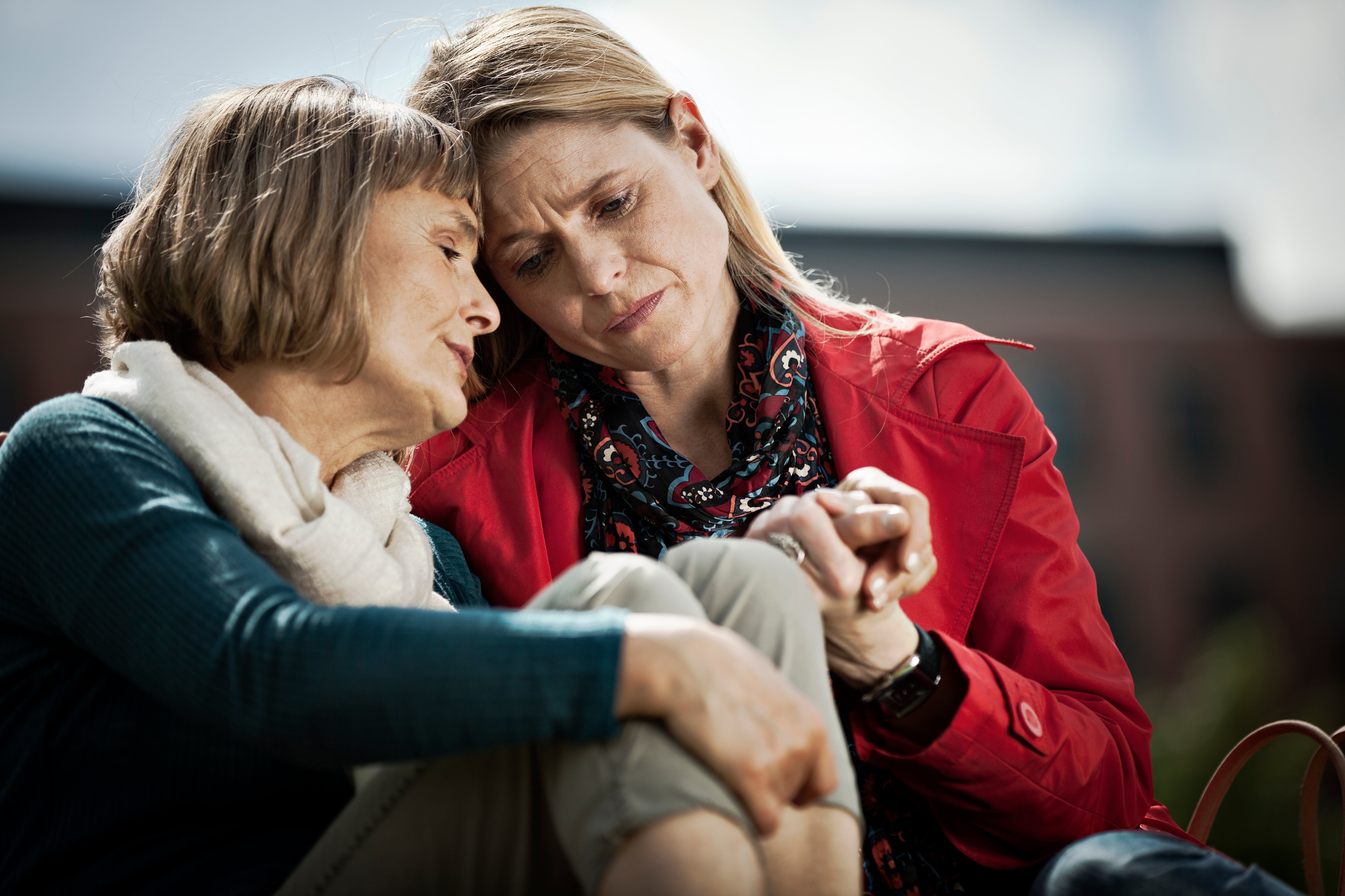 Mother and Daughter sharing an emotional moment on a bench outside