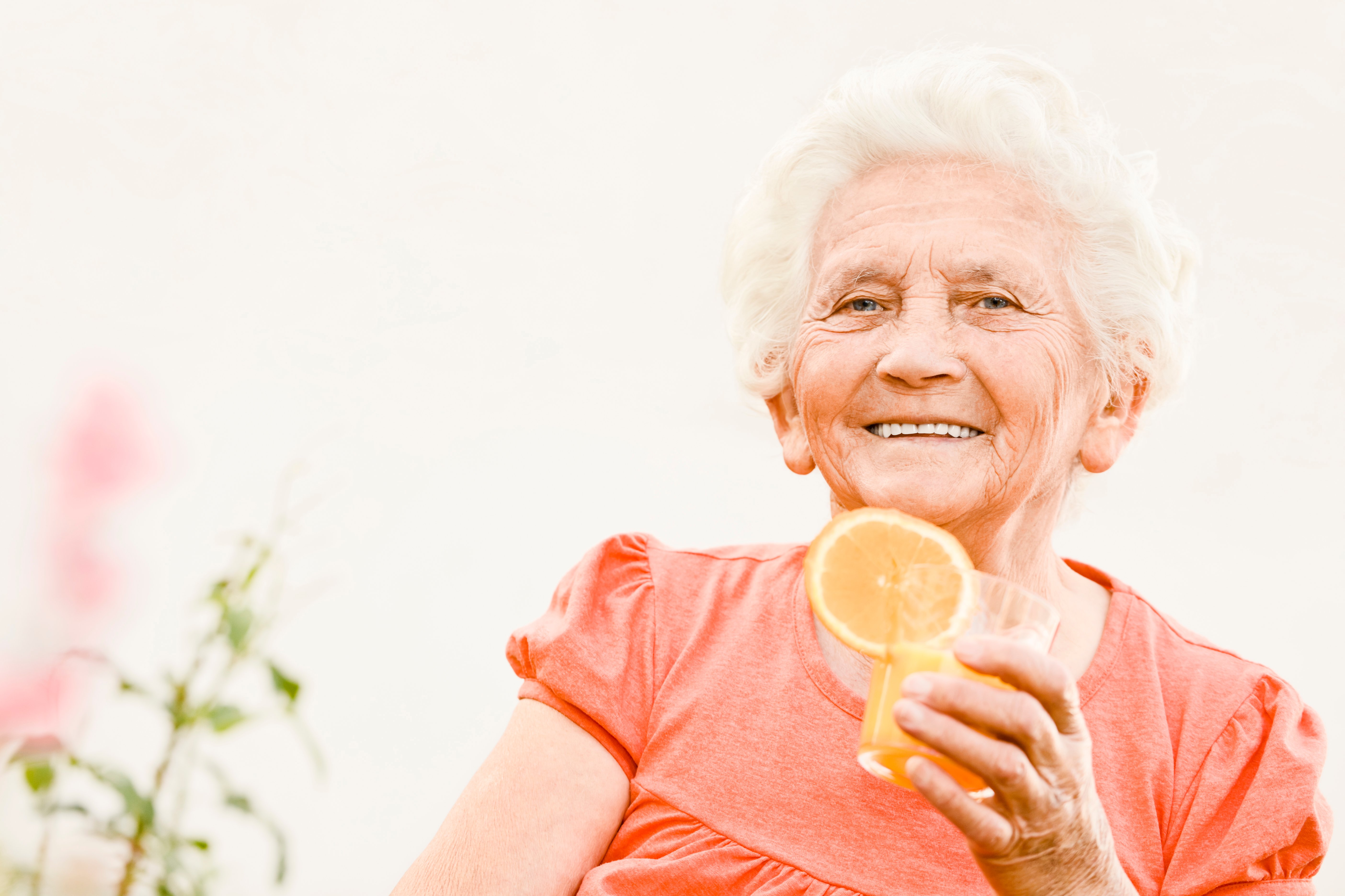 Elderly women drinking orange juice and smiling for a photo