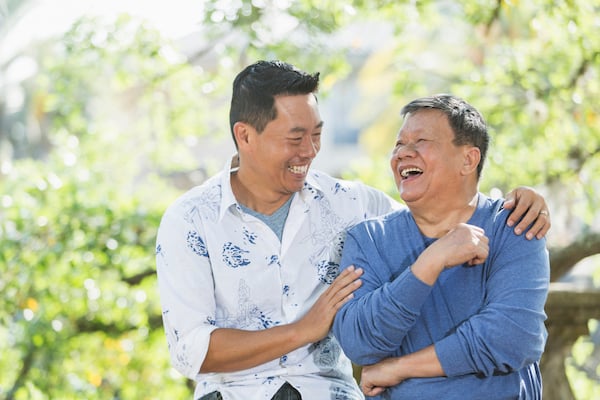 Adult son laughing with his elderly father