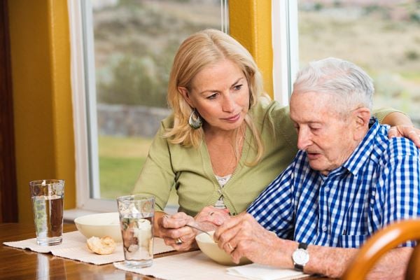 Daughter eating breakfast with her father and providing comfort to him