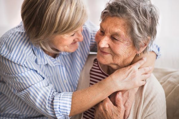 daughter holding her arms around her mothers neck giving her a hug