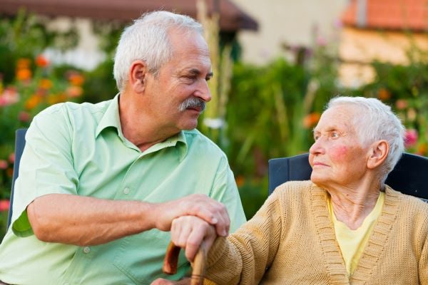 Mother and son sitting outside while son is holding mothers hand. both of them are looking at one another