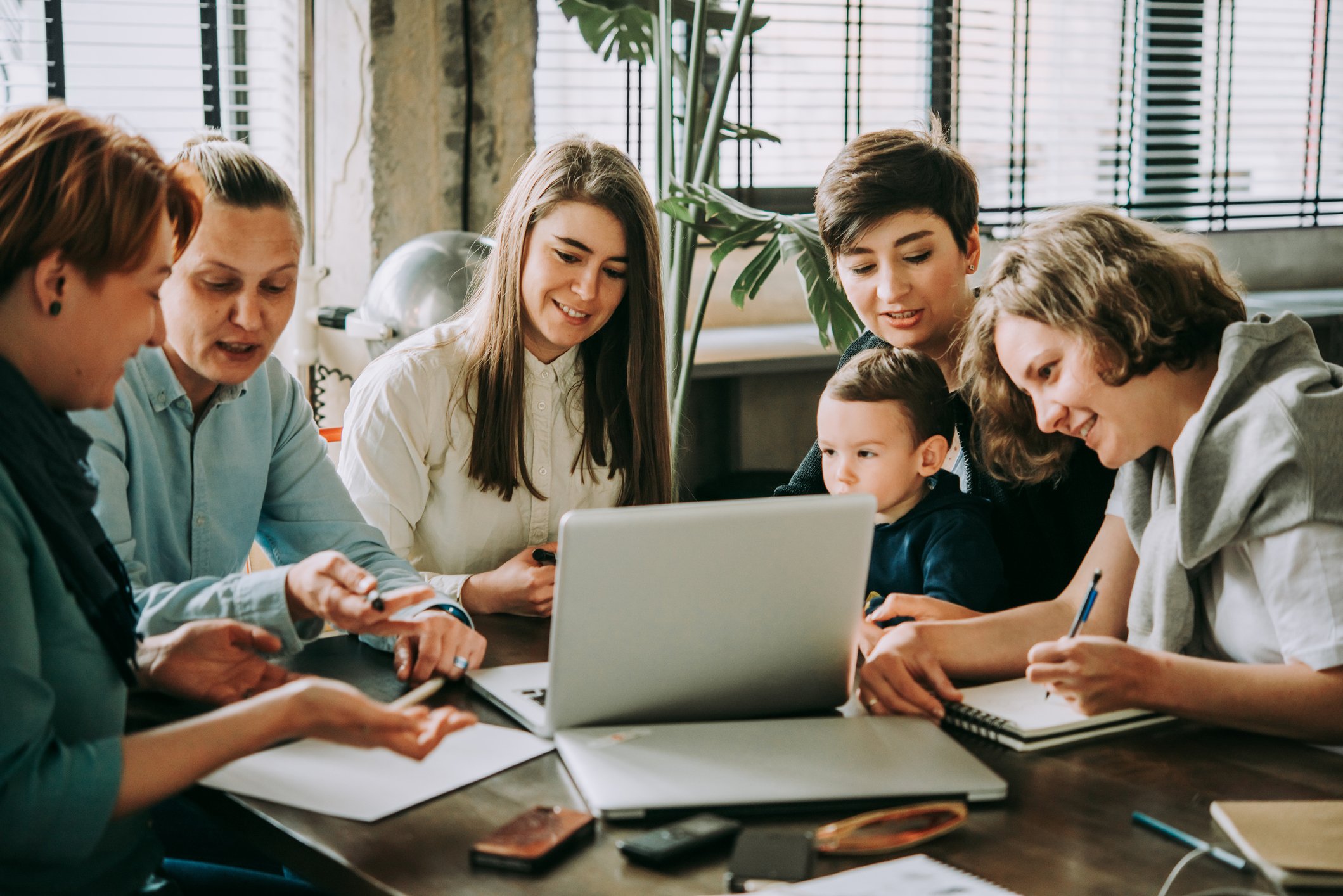 Family looking at a computer screen together while writing on paper and figuring out family things