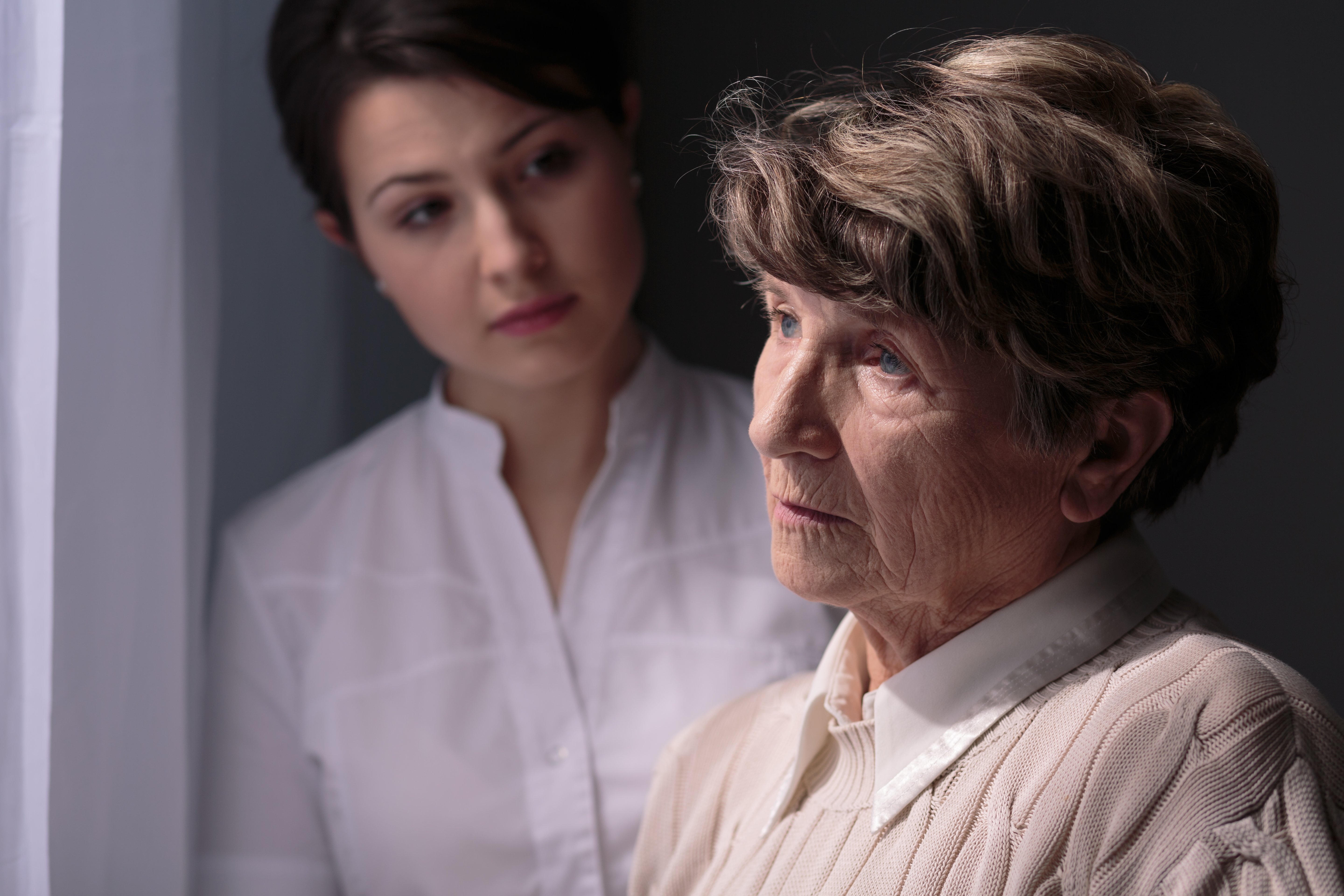 daughter and mother looking out the window together with depressed faces