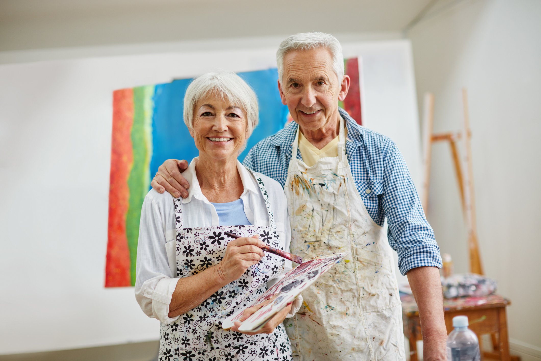 Husband and wife painting together and smiling for a photo