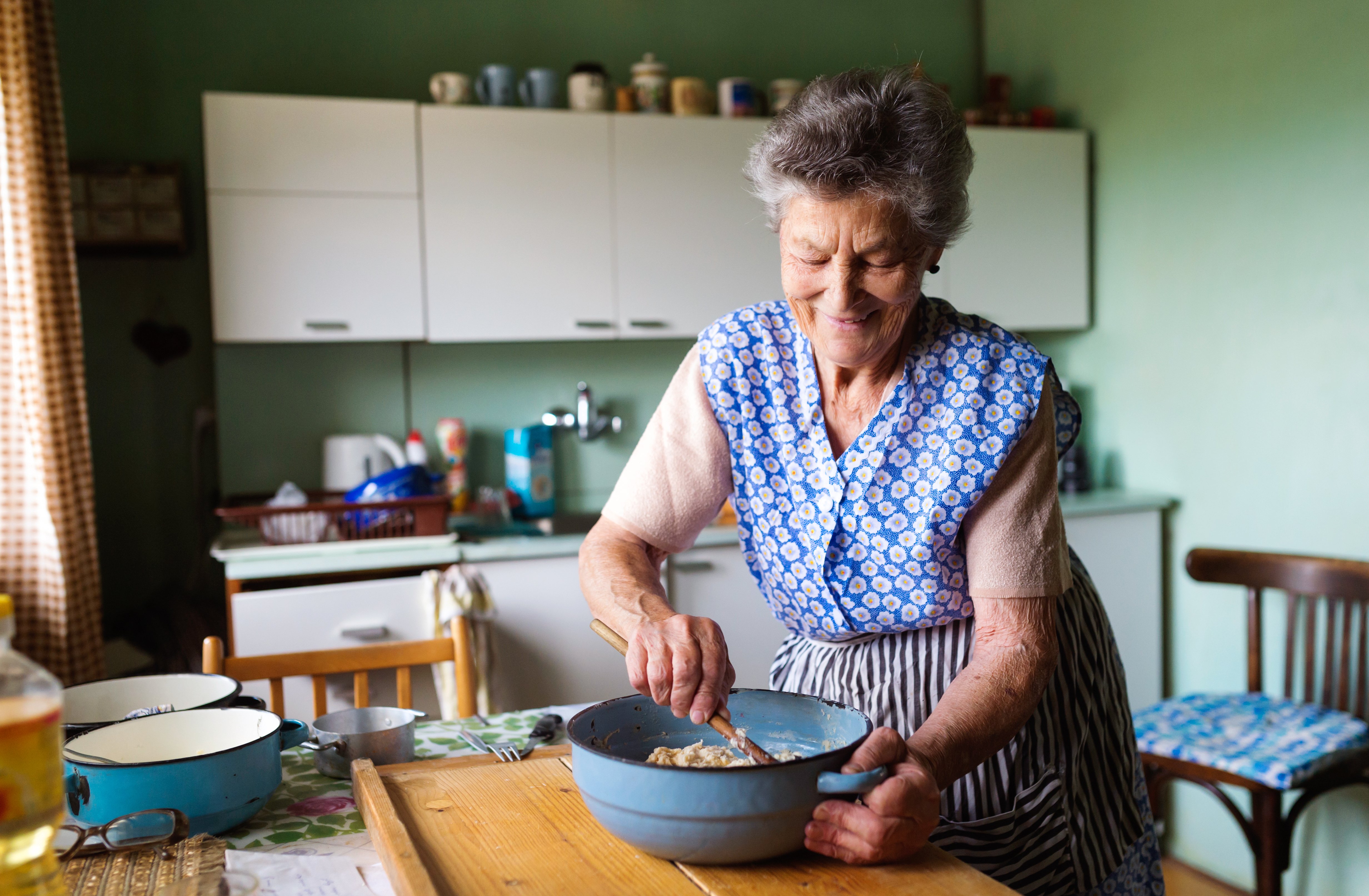 Elderly women baking in her kitchen with a smile on her face