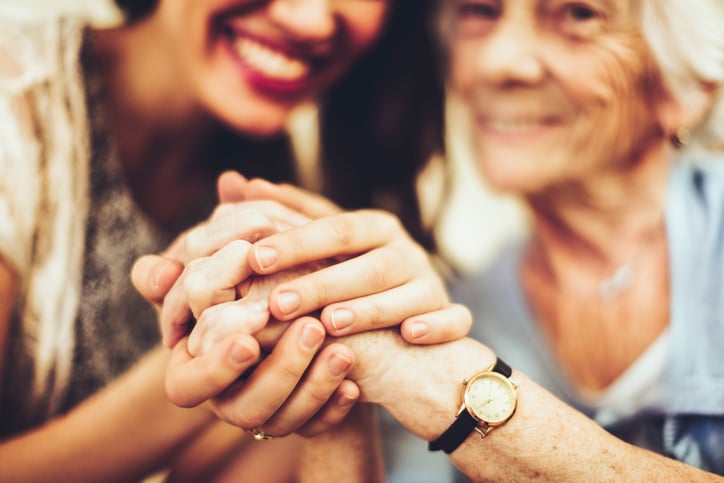 Mother & daughter holding each others hands in front of them. Main focus is on their hands